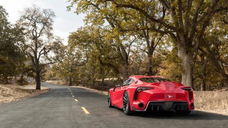 Sleek Red Sports Car on a Scenic Roadway wallpaper