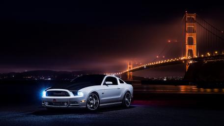 Sleek Mustang Against Iconic Bridge at Night wallpaper