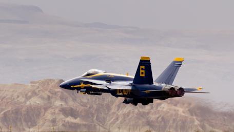 Fighter Jet Soaring Through Rugged Terrain wallpaper