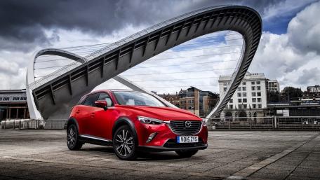 Sleek Red Car Under Iconic Bridge Design wallpaper
