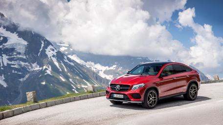 Sleek Red SUV Against Majestic Mountainside wallpaper