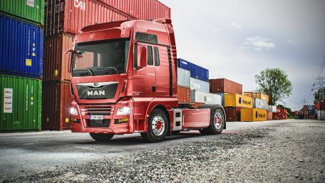 Bold Red Truck Amidst Shipping Containers wallpaper