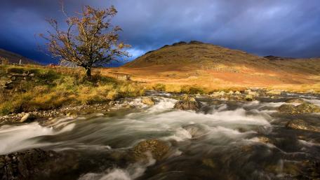 Majestic Mountain Stream Under Dramatic Skies wallpaper