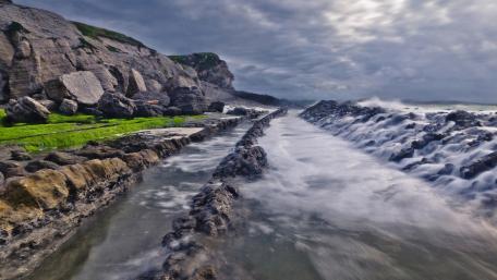 Serene Coastal Scene with Gentle Waves and Rocky Outcrops wallpaper