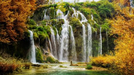 Serene Autumn Waterfall Scene with Vibrant Foliage wallpaper