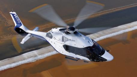 Sleek Helicopter in Flight Over Coastal Landscape wallpaper
