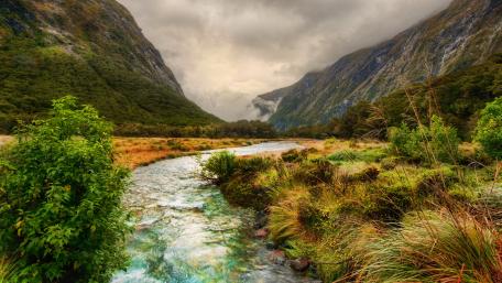 Tranquil Mountain Stream Amidst Lush Valley wallpaper