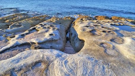 Majestic Rocky Shoreline Under Blue Skies wallpaper