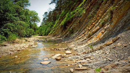 Serene Stream Amidst Majestic Cliffs wallpaper