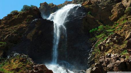 Majestic Waterfall Cascading Down Rugged Cliffs wallpaper