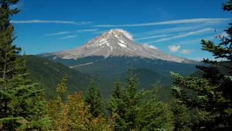 Majestic Mountain Surrounded by Lush Forests and Clear Skies wallpaper