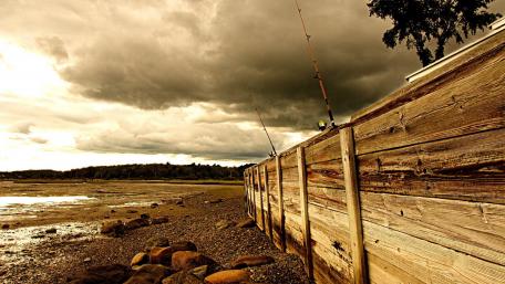 Whimsical Fishing Shoreline Under Ominous Skies wallpaper