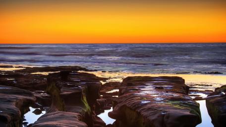 Serene Sunset Over Rocky Shoreline wallpaper