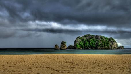 Serene Beach with Dramatic Clouds and Island View wallpaper