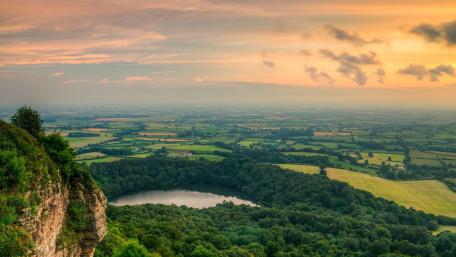 Breathtaking Sunset Over Rolling Hills and Tranquil Lake wallpaper