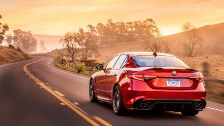 Sleek Red Car on Scenic Roadviewing Sunset Glow wallpaper