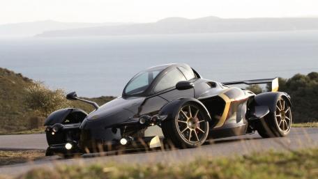 Sleek Black Supercar on Scenic Roadway wallpaper