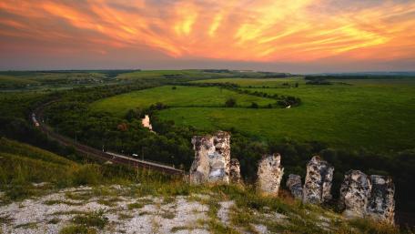 Serene Sunset Over Rolling Green Hills and Cliffs wallpaper