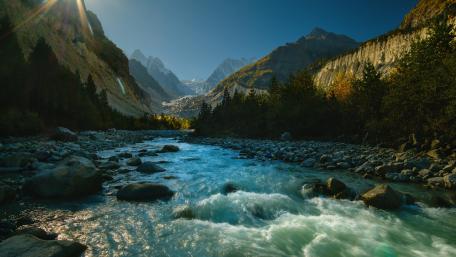 Serene Mountain River Flowing Through Majestic Landscapes wallpaper