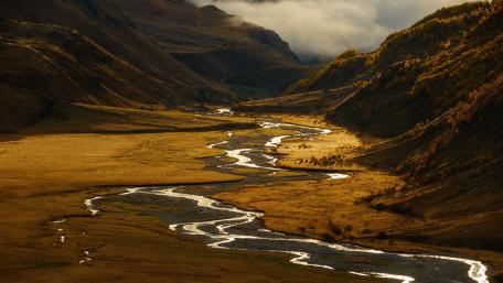Serene River Flowing Through Golden Valleys wallpaper