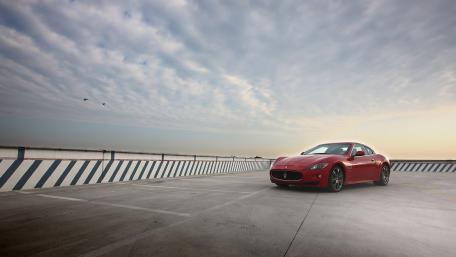 Sleek Red Car Under Dramatic Sky View wallpaper