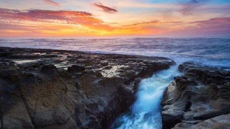 Serene Ocean Sunset Over Rugged Rocks wallpaper