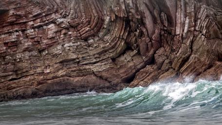 Waves Embracing Ancient Rock Layers wallpaper