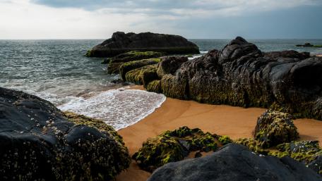 Serene Shoreline with Rugged Rocks and Gentle Waves wallpaper