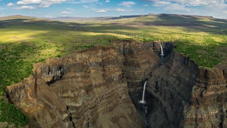Majestic Waterfall Cascading into a Vast Canyon Ahead of the Horizon wallpaper