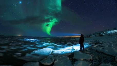 Majestic Northern Lights Dance Over Icy Landscape wallpaper