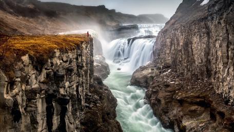 Majestic Waterfall and Rugged Cliffs in Nature's Embrace wallpaper