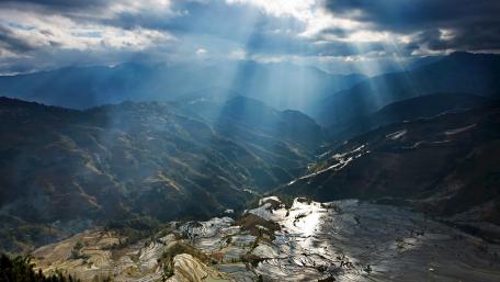Majestic Terraced Fields Under Cloudy Skies wallpaper