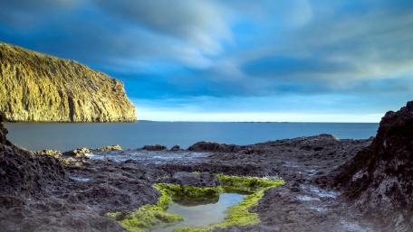 Serene Coastal Landscape with Rocky Shoreline and Calm Waters wallpaper