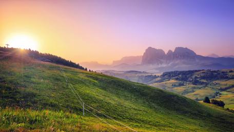 Serene Sunrise over Majestic Mountains and Green Hills wallpaper