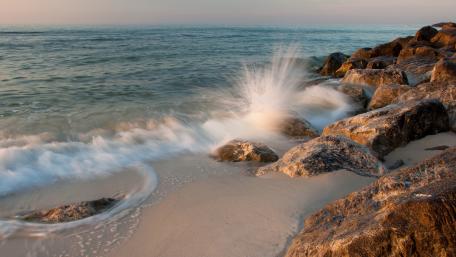 Serene Waves Embracing Rocky Shores wallpaper