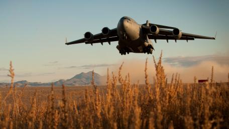Majestic Military Aircraft in Flight over Open Fields wallpaper