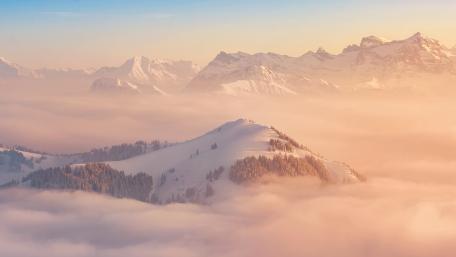 Majestic Snowy Mountains Under Soft Sunrise Glow wallpaper