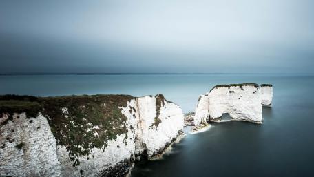 Majestic Coastal Cliffs Under Soft Gray Skies wallpaper