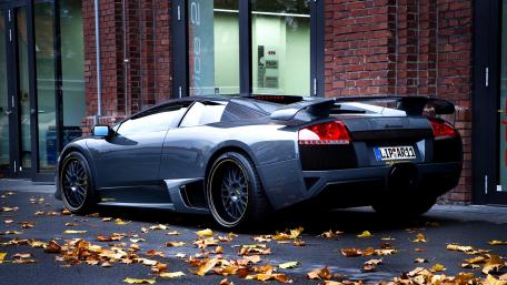 Sleek Gray Supercar Among Autumn Leaves wallpaper