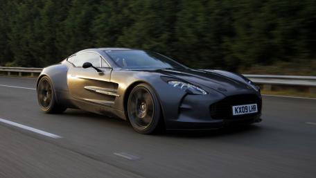 Sleek Black Supercar in Motion on a Scenic Road wallpaper