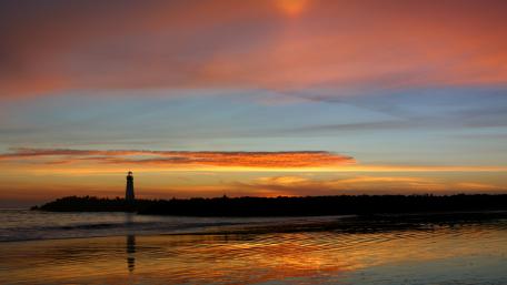 Lighthouse at Sunset Over Calm Waters wallpaper