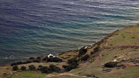 Serene Coastal Landscape with Rolling Waves and Green Hills wallpaper