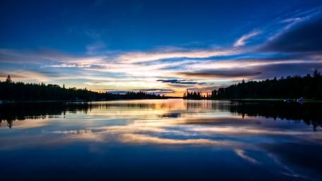 Serene Sunset Reflections Over Calm Lake Waters wallpaper