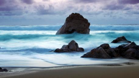 Serene Ocean Waves Embracing Rocky Shoreline wallpaper