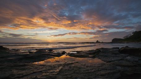 Serene Sunset Over Rocky Shoreline wallpaper