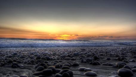 Serene Sunset Over Pebbled Shoreline wallpaper