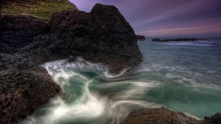 Serene Coastal Waves Embrace Rocky Shores wallpaper