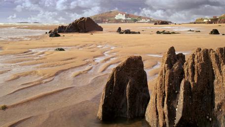 Serene Beachscape with Rocky Outcrops and Cloudy Sky wallpaper
