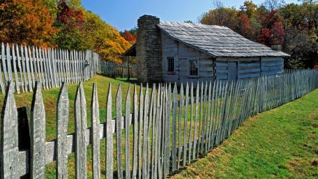 Rustic Cabin Surrounded by Autumn Foliage and Fencing wallpaper