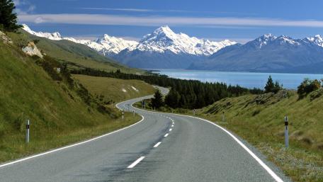 Scenic Road Leading to Majestic Mountains and Lake Waters wallpaper